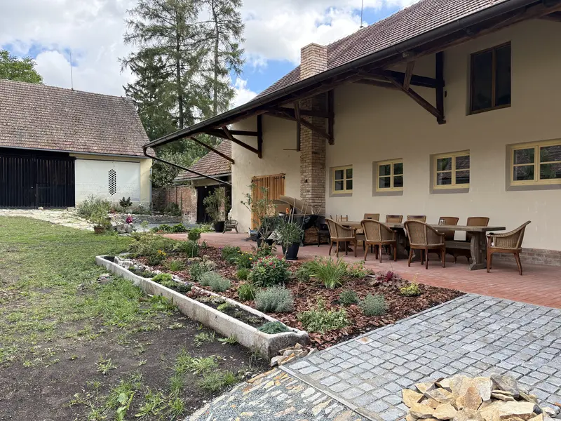Zastřešené posezení s dlouhým stolem na dvoře před sálem